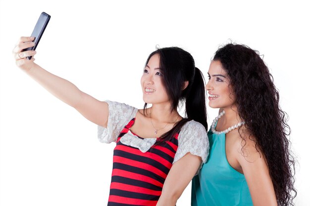 Amigos tirando selfie com telefone celular contra um fundo branco