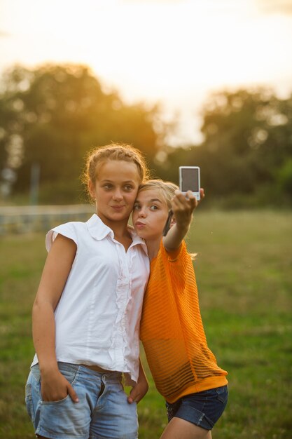 Foto amigos tirando um auto-retrato ao ar livre. duas garotas fazendo selfie no brilho do verão