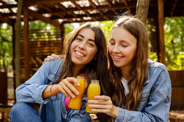 Foto amigos de tiro medio con botellas de jugo fresco