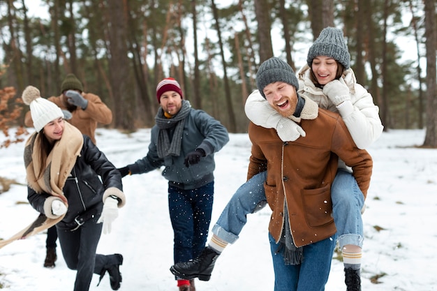 Foto amigos de tiro medio divirtiéndose con la nieve.