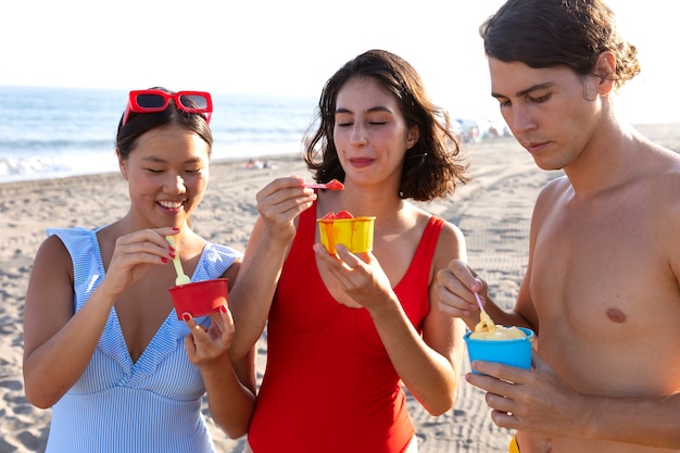 Foto amigos de tiro medio con helado en la playa.