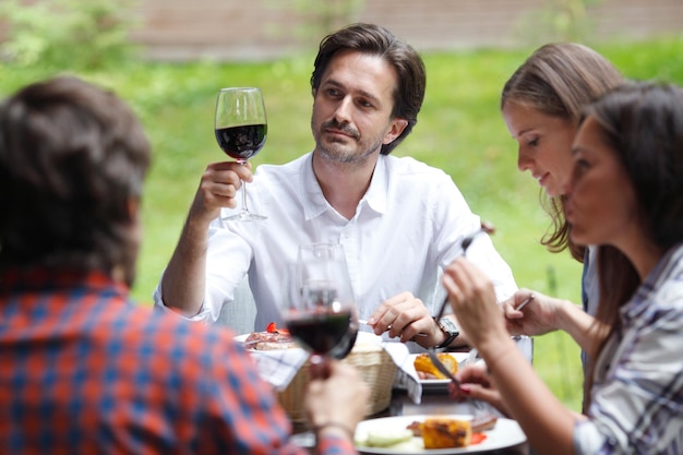 Amigos tocam taças de vinho tinto no jantar ao ar livre