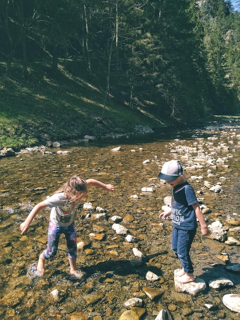 Foto amigos de toda la longitud jugando en el arroyo