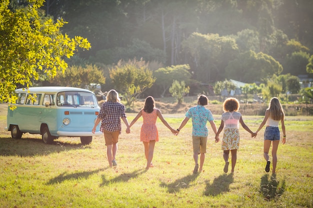 Amigos tomados de la mano y caminando en el parque