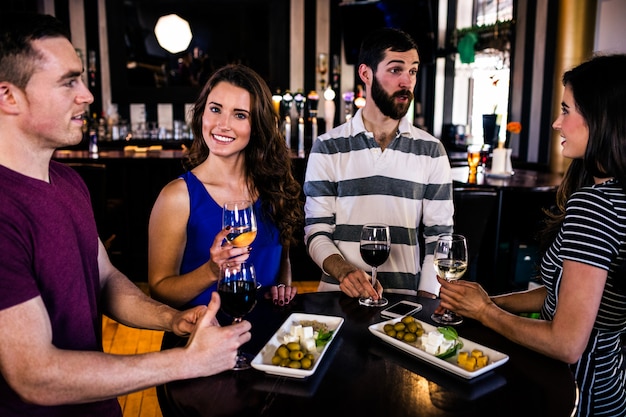 Amigos tomando un aperitivo con vino en un bar