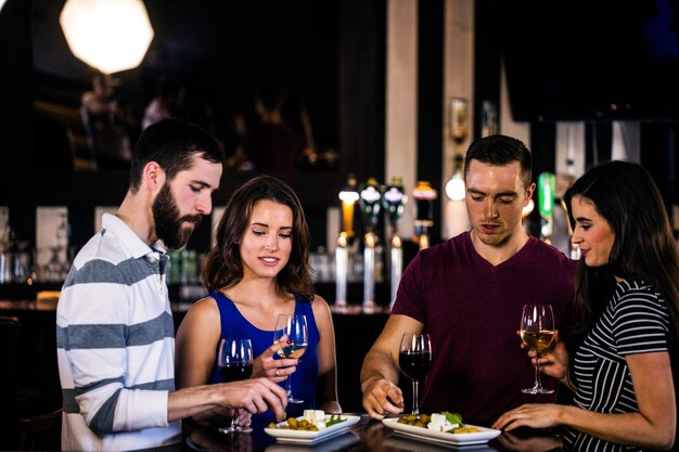 Amigos tomando un aperitivo con vino en un bar