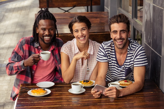 Foto amigos tomando café y usando el teléfono inteligente