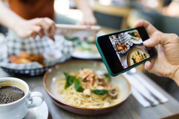 Foto amigos tomando fotos en un plato en el restaurante