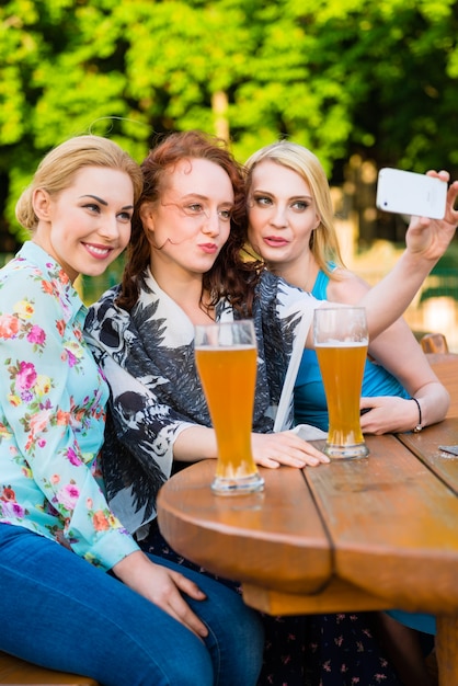Amigos tomando selfie con teléfono inteligente en el jardín de la cerveza