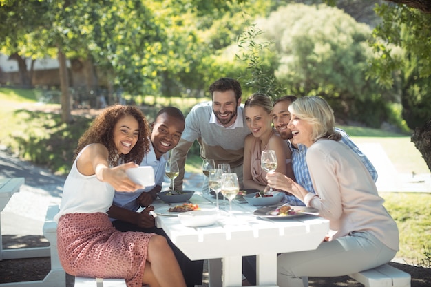 Amigos tomando selfie en teléfono móvil mientras come