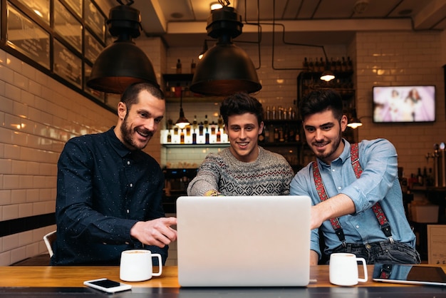 Amigos usando o laptop no café.