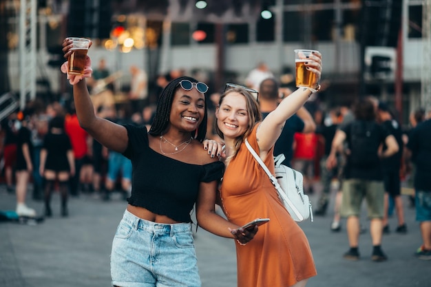 Amigos usando smartphone e bebendo cerveja em um festival de música