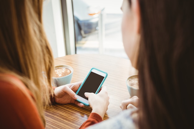 Amigos usando smartphone e tomando café em uma cafeteria