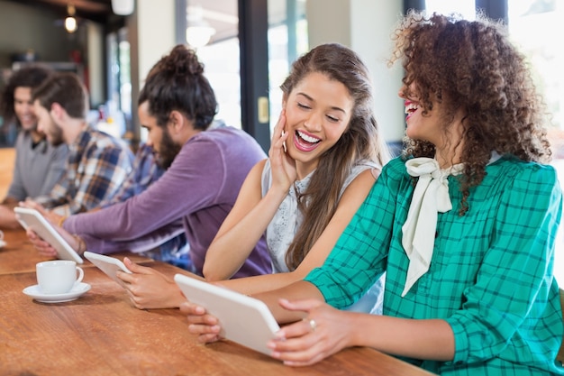 Amigos usando tableta digital mientras está sentado en el restaurante