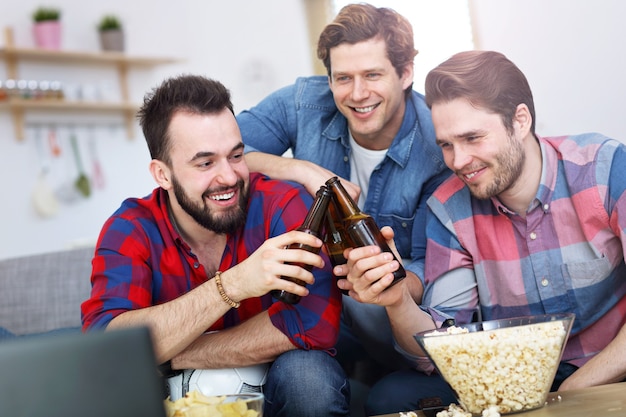 amigos varones felices animando y viendo deportes en la televisión