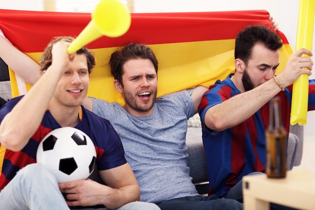 amigos varones felices animando y viendo deportes en la televisión