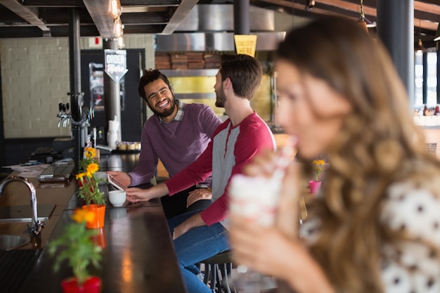 Amigos varones hablando mientras está sentado en el restaurante