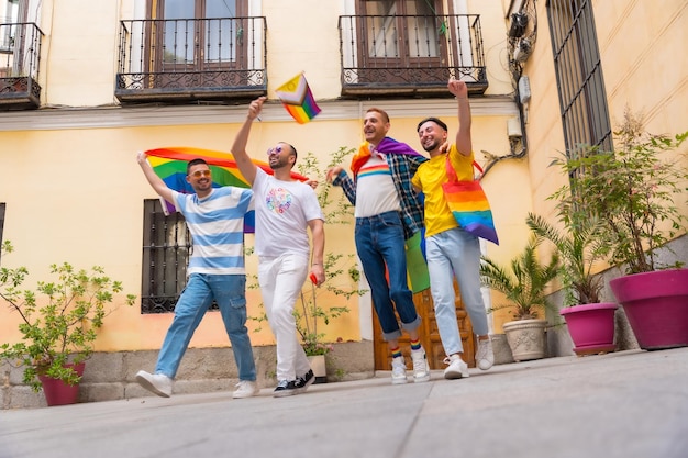 Amigos varones homosexuales que se van de casa a la fiesta del orgullo gay diversidad de jóvenes en el camino de la ciudad a la manifestación con las banderas del arco iris concepto lgbt