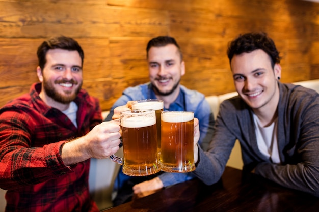 Amigos varones tostando cerveza en el restaurante