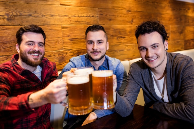 Amigos varones tostando cerveza en el restaurante