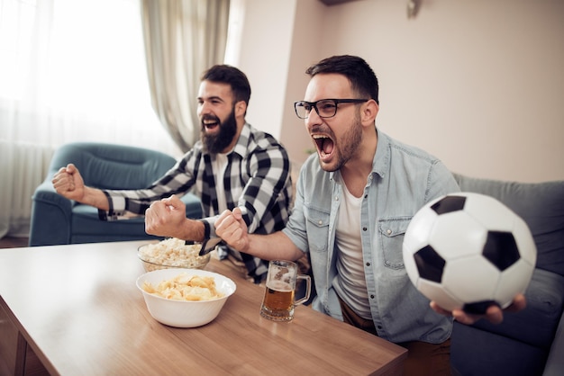 Amigos viendo deportes en la televisión