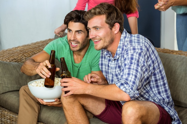 Amigos viendo un partido de fútbol en la televisión en casa