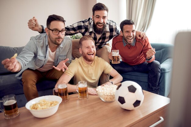 Amigos viendo partido de fútbol en la televisión