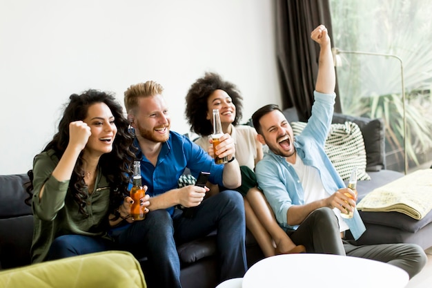 Foto amigos viendo la televisión, bebiendo sidra y divirtiéndose en la habitación