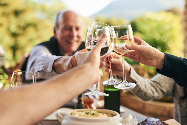 Amigos vino y brindis en un patio con gente feliz y alegre celebrando y compartiendo una comida al aire libre Manos familiares y vítores en celebración de la fiesta tradicional y feliz reunión familiar