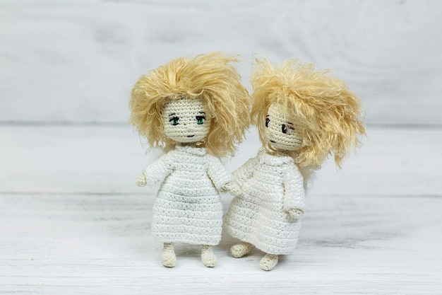 Amigurumi de brinquedo de malha angeles em fundo branco de madeira