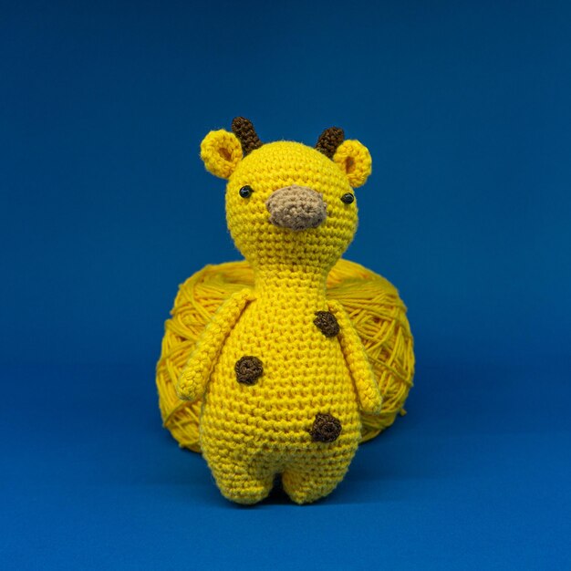 Amigurumi de girafa sobre fundo azul.