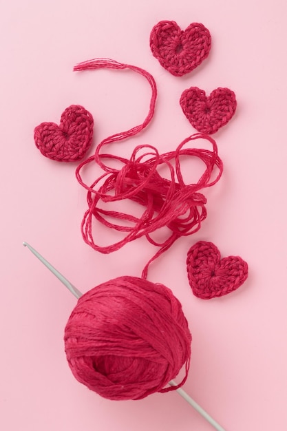 Amigurumi de ganchillo corazón rojo burdeos morado con ganchillo sobre fondo rosa San Valentín
