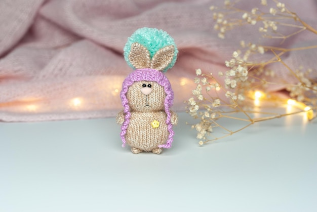 Foto amigurumi-hase auf dem hintergrund eines warmen schals und einer getrockneten blume