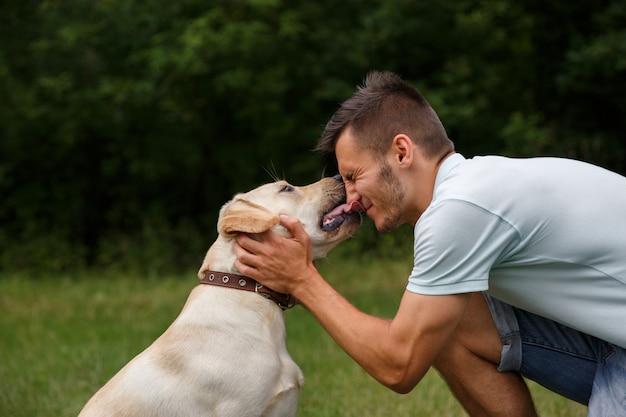 Amistad y amor del hombre y el perro. Feliz joven besándose con su amigo - perro Labrador