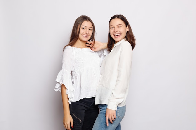 Amistad, camiseta designe y concepto de gente feliz. dos niñas riendo en camisetas blancas en blanco