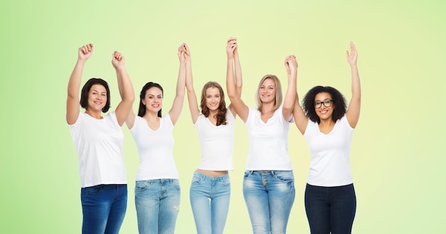 amistad, diversidad, cuerpo positivo y concepto de la gente - grupo de mujeres felices de diferentes tamaños en camisetas blancas sosteniendo las manos sobre fondo natural verde