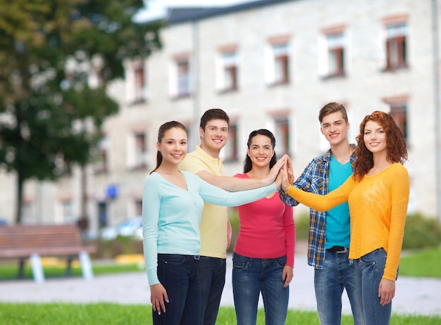 amistad, educación, trabajo en equipo, gesto y concepto de la gente - grupo de adolescentes sonrientes que chocan cinco sobre el fondo del campus