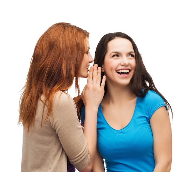 amistad, felicidad y concepto de la gente - dos chicas sonrientes susurrando chismes