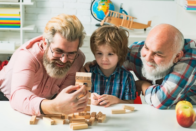 Amistad de generaciones masculinas Abuelo enseñando a su nieto a jugar juegos de Jenga Familia de hombres Generación de tres hombres Jugando Jenga