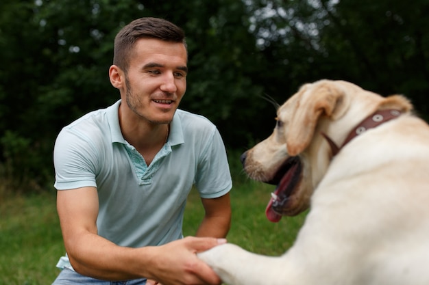 Foto la amistad del hombre y el perro. feliz joven sosteniendo una pata de un perro labrador