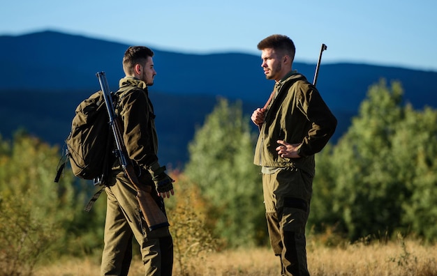 Amistad de hombres cazadores. Uniforme militar. Fuerzas del ejército. Camuflaje. Habilidades de caza y equipamiento de armas. Cómo convertir la caza en hobby. Cazadores de hombre con rifle. Campo de entrenamiento. Cazador con arma.