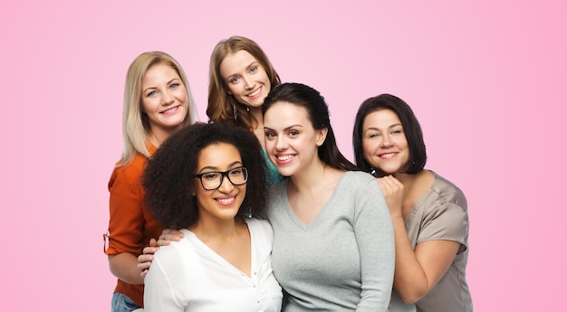 amistad, moda, cuerpo positivo, diverso y concepto de personas - grupo de diferentes mujeres felices con ropa informal sobre fondo rosa