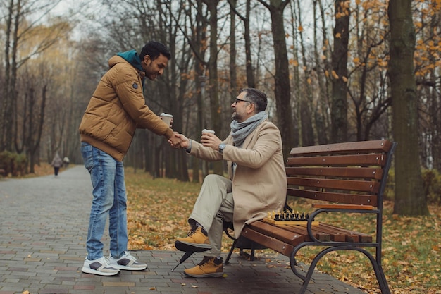 Amistad multicultural de personas de diferentes edades Una reunión de dos amigos para jugar al ajedrez en el parque