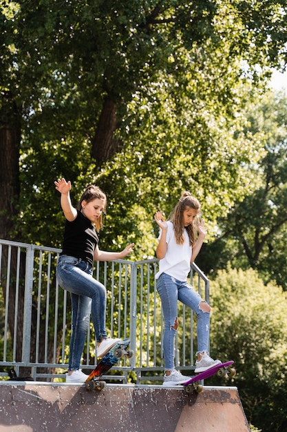 Amistad de los niños Chicas amigas listas para montar en penny board en el parque de patinetas Equipo deportivo para niños Estilo de vida extremo