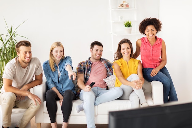 amistad, ocio, comida chatarra, gente y concepto de entretenimiento - amigos felices con televisión remota en casa