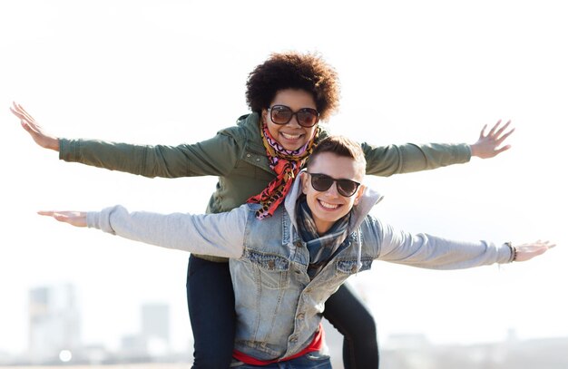 amistad, ocio, internacional, libertad y concepto de personas - feliz pareja adolescente en sombras divirtiéndose al aire libre