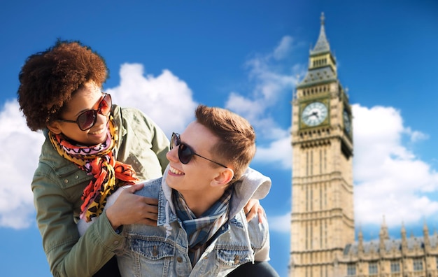 Amistad, ocio, internacional, libertad y concepto de personas - feliz pareja adolescente en sombras divirtiéndose sobre el fondo de la torre Big Ben de Londres