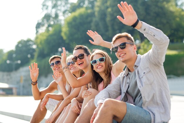 amistad, ocio, verano, gesto y concepto de personas - grupo de amigos sonrientes sentados en la plaza de la ciudad