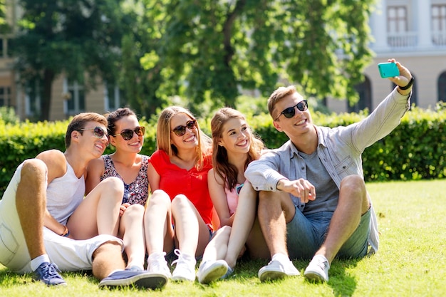 amistad, ocio, verano, tecnología y concepto de personas - grupo de amigos sonrientes con smartphone haciendo selfie en el parque
