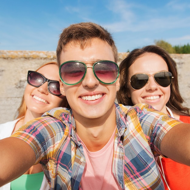 amistad, ocio, verano, tecnología y concepto de personas - grupo de amigos sonrientes tomando selfie al aire libre